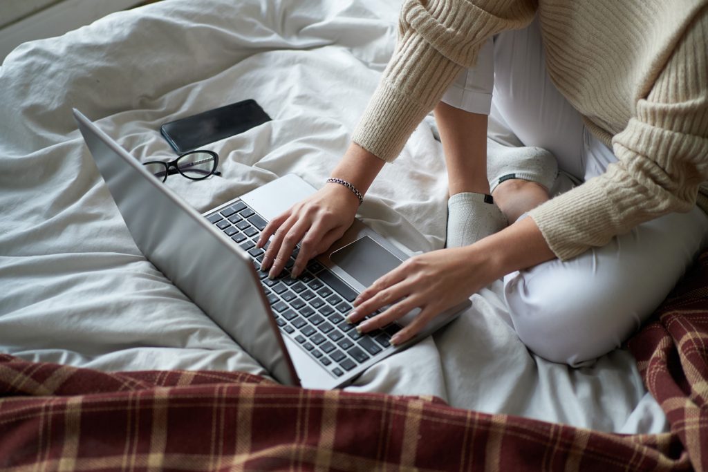 Girl working from bed at home on laptop